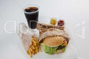 Close-up of hamburger, french fries, sauce and cold drink