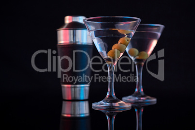Cocktail martini with olives and shaker on table
