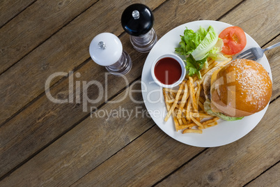 Burger, french fries, sauce in plate on wooden table