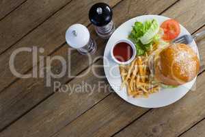 Burger, french fries, sauce in plate on wooden table