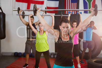 Young athletes lifting barbells against flags