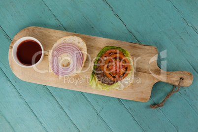 Overhead of hamburger and sauce on chopping board
