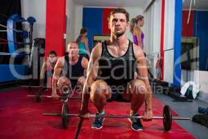 Young athletes crouching with barbells