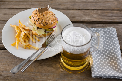 Cheeseburger with fries served in plate by beer glass