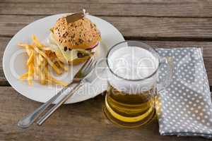 Cheeseburger with fries served in plate by beer glass