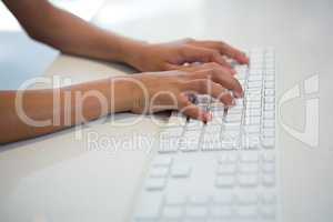 High angle view of girl typing on white computer keyboard