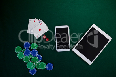 Electronic gadgets, playing cards, mobile phone, dice and casino chips on poker table