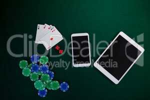 Electronic gadgets, playing cards, mobile phone, dice and casino chips on poker table