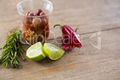 Pickled olives, rosemary with lemon and red chilies on table