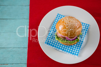Overhead view of hamburger served on napkin in plate