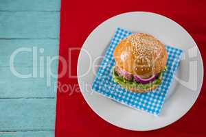 Overhead view of hamburger served on napkin in plate