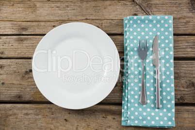 Overhead view of empty plate by napkin and eating utensils