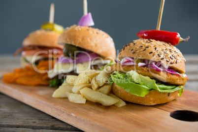 Various burgers with Frenc fries on cutting board