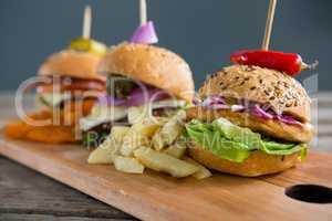Various burgers with Frenc fries on cutting board