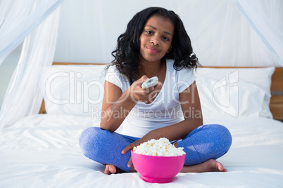 Girl holding remote control while watching television