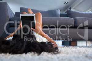 Girl using tablet computer while lying on rug
