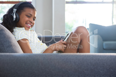 Portrait of girl listening music while using tablet computer