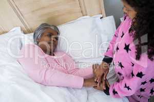 Granddaughter comforting sick grandmother in bed room