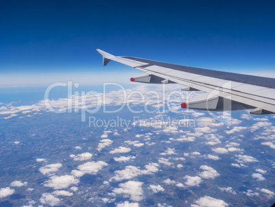 View from a plane window: a plane wing over clouds and blue sky
