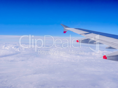 View from a plane window: a plane wing over clouds and blue sky