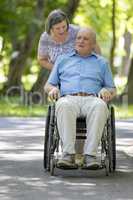 Senior woman pushing husband in wheelchair