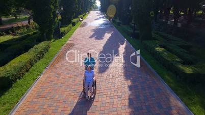 Aerial footage of caregiver walking with disabled senior in wheelchair