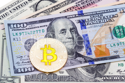 Closeup of golden yellow bitcoin on hundred dollars banknote, ma