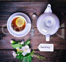 Black tea with lemon and white tea pot