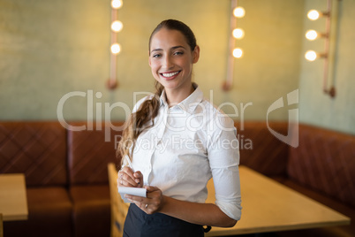 Smiling waitress taking an order on notepad in bar