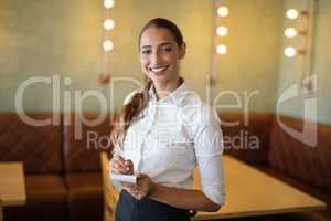Smiling waitress taking an order on notepad in bar