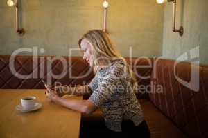 Beautiful woman using mobile phone at table