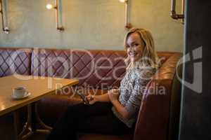 Smiling beautiful woman using mobile phone in restaurant