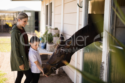 Mother and daughter feeding a horse in the stable