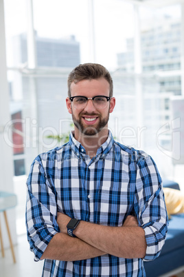 Male executive standing with arms crossed in office