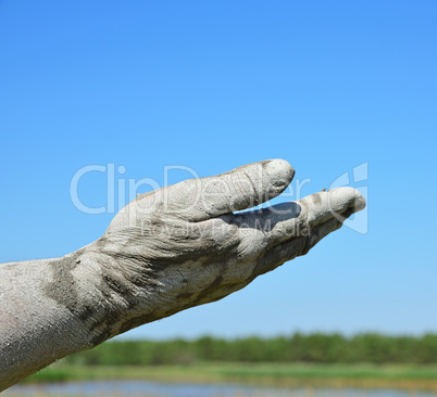 Man's hand in the mud extended forward