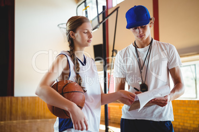 Female basketball player discussing with male coach