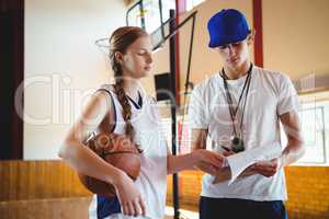 Female basketball player discussing with male coach