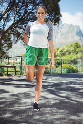 Portrait of smiling woman exercising on road