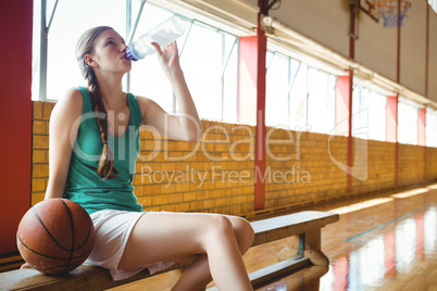 Woman drinking water while sitting on bench