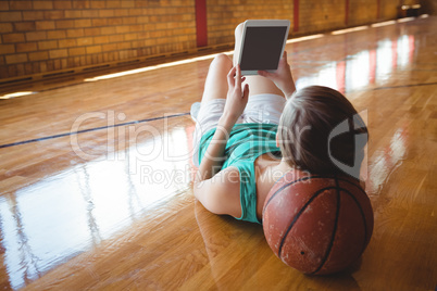 Woman using digital tablet while lying on floor