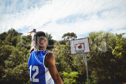 Rear view of male teenager practicing basketball