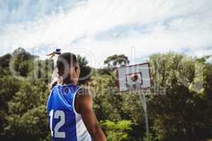 Rear view of male teenager practicing basketball