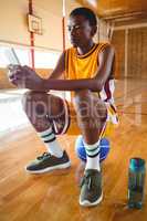 Teenage boy using mobile phone while sitting on ball