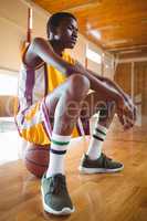 Thoughtful teenage boy sitting on basketball