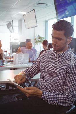 Businessman using digital tablet with colleagues discussing in background