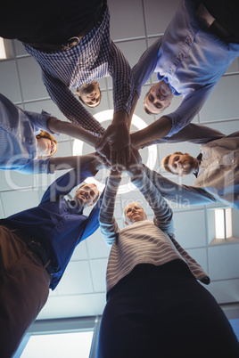 Directly below shot of business colleagues stacking hands at office