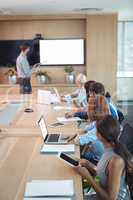 Business people using laptop and digital tablets at conference table during meeting