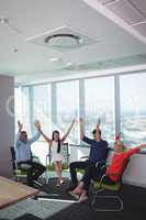 Cheerful business people with arms raised at office