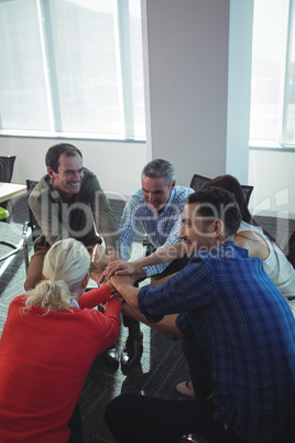 Happy business people stacking hands at office