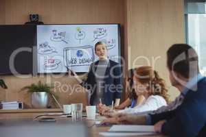 Businesswoman discussing with colleagues over whiteboard during meeting